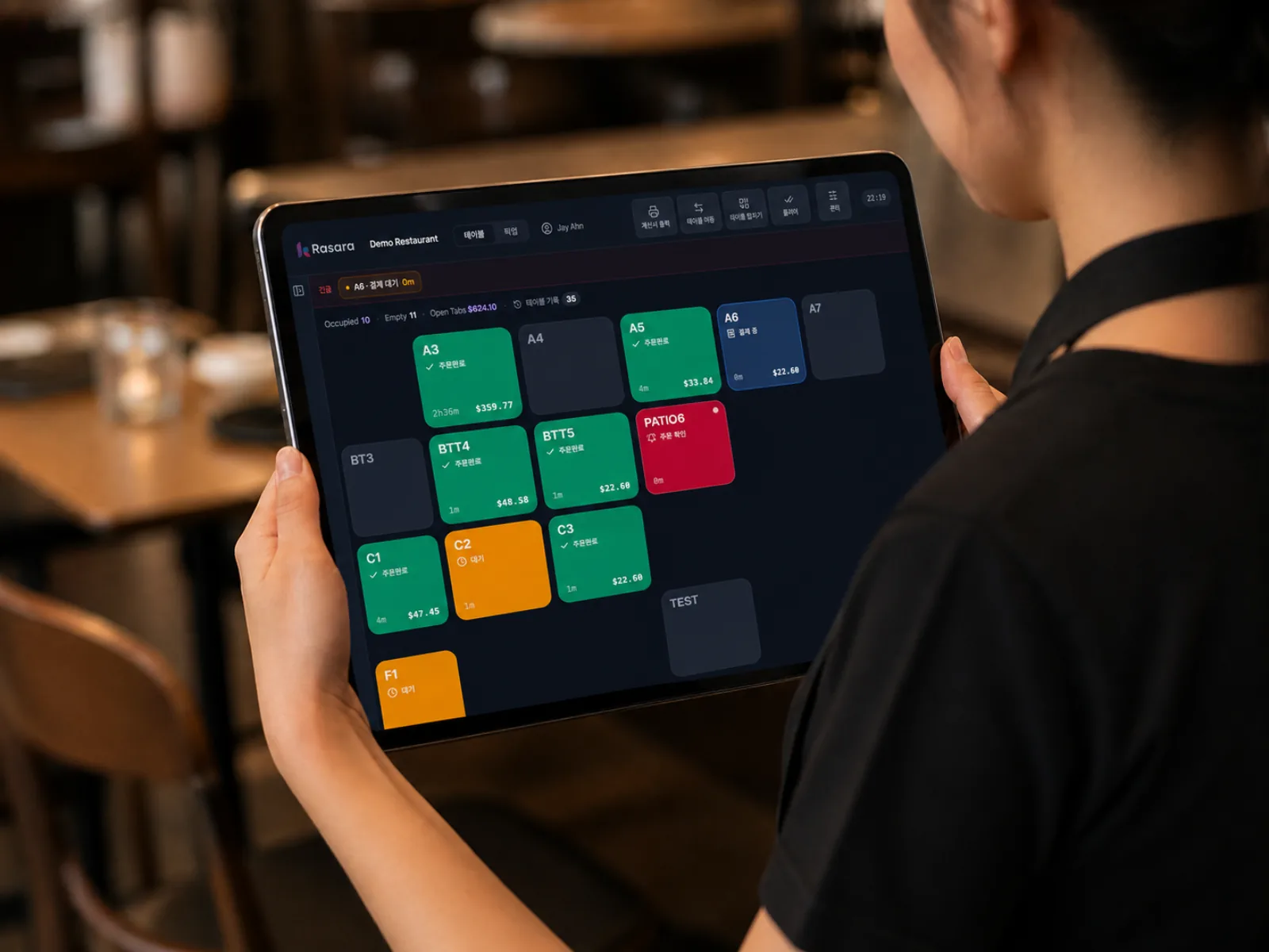 A server holding a tablet that shows the status of each table
